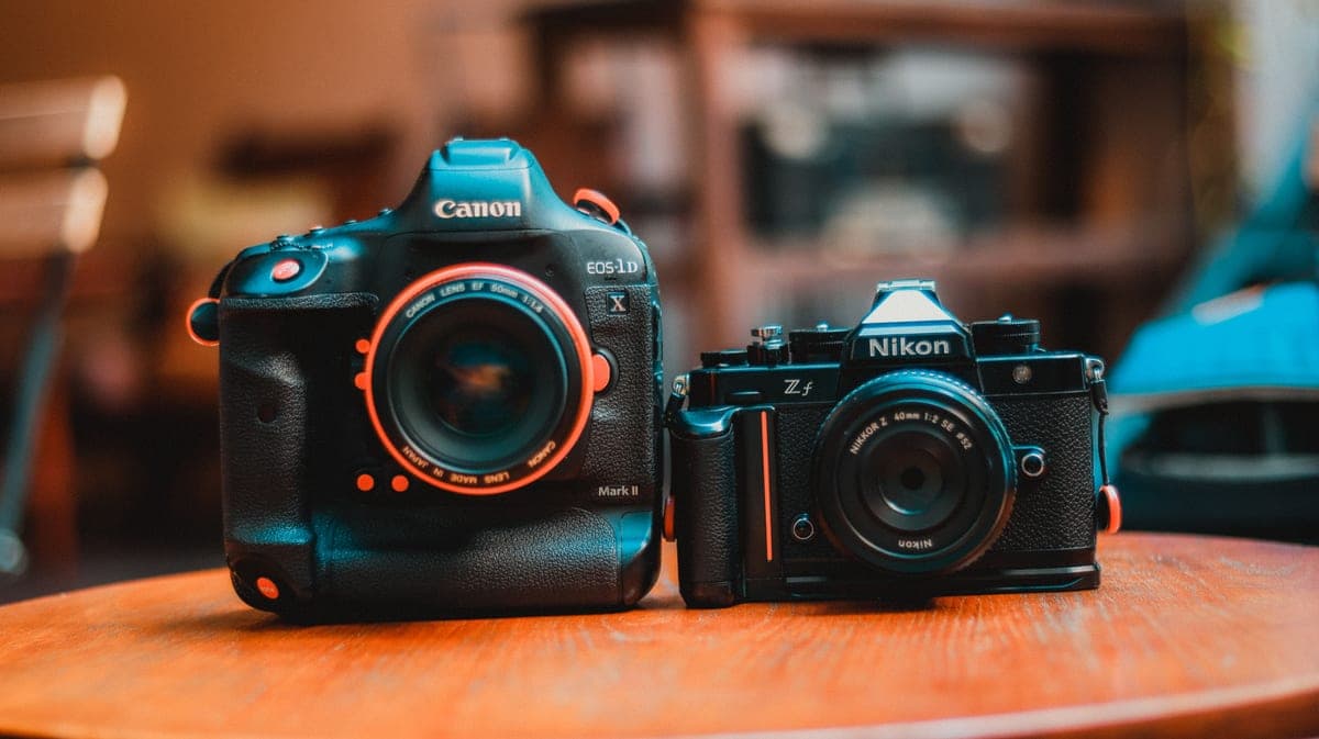 A notebook, a camera and lenses arranged on a desk as if planning a purchase