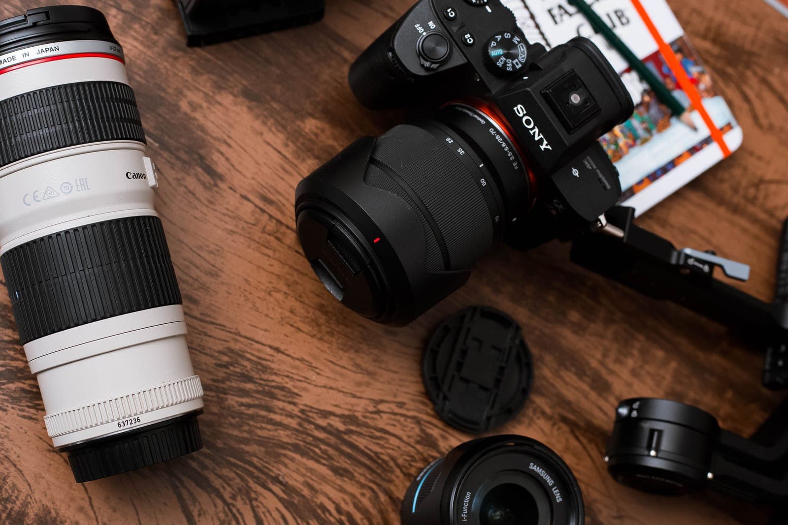 A mirrorless camera and two lenses on a warm wooden table in golden-hour light